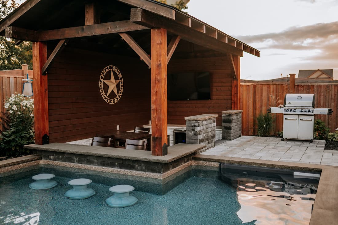 Inground pool with swim-up seats at an integrated grill and dining area.